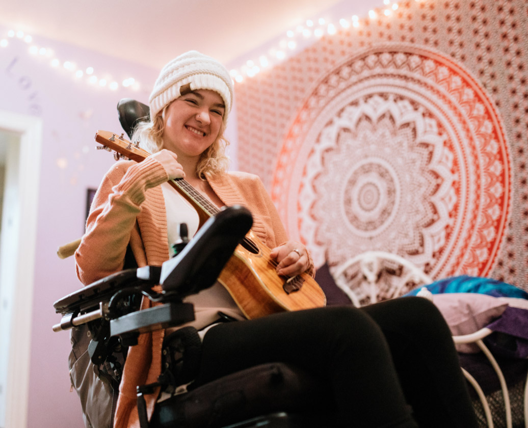 Woman in wheelchair with ukulele and beanie