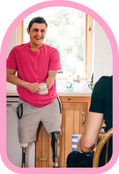 Smiling man in pink tshirt with cup in hand.